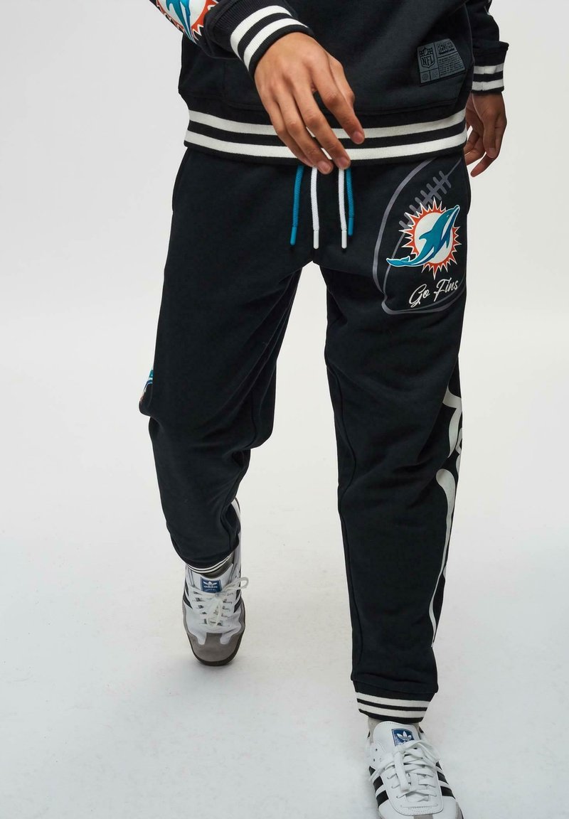 Schwarze Sweatpants mit blauen Kordeln, ausgestattet mit dem Logo der Miami Dolphins und dem Text "Go Fins". Gestreifte Bündchen und seitliche Einsätze verleihen dem Design zusätzlichen Pfiff.