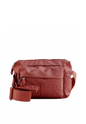 Sac bandoulière en tissu rouge texturé avec une poche avant zippée, une sangle réglable et un lettrage embossé sur la poche avant.