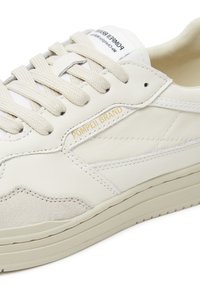 White leather sneakers with suede accents, round toe, and lace closure. Features "Pompeii Brand" in gold on the side. Textured outsole.
