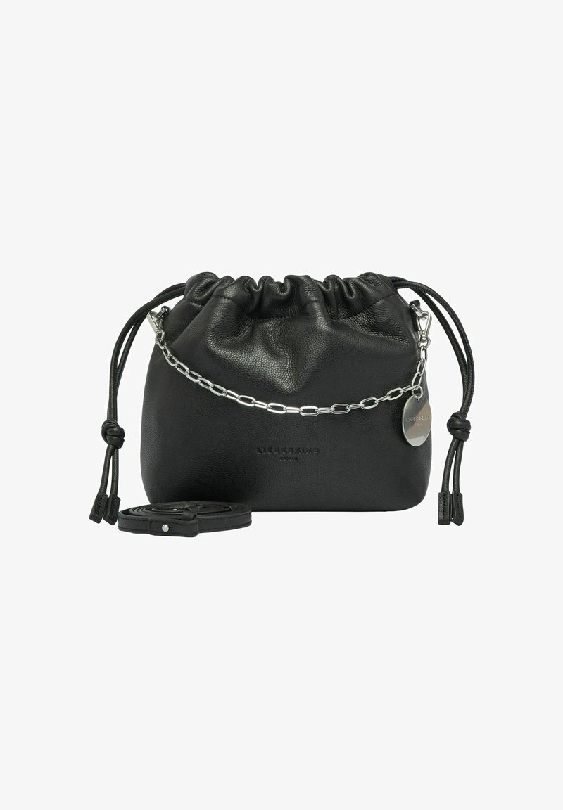 Schwarze Lederzugtasche mit silberner Kette und rundem Metalletikett, flach liegend mit abnehmbarem Schultergurt, der neben ihr aufgerollt liegt.