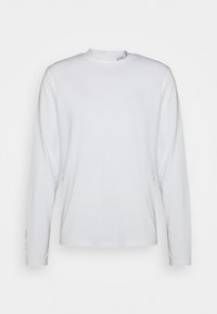 En enkel vit långärmad T-shirt med rund halsringning och diskret logotypdetalj vid kragen och nära handleden, visad mot en neutral bakgrund.