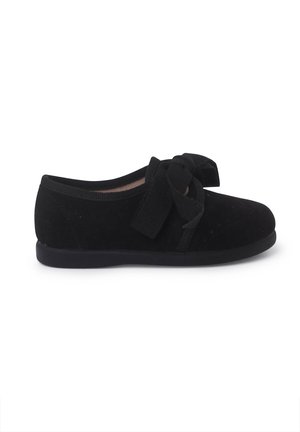 Bailarinas de ante negro con punta redonda, superficie texturizada y un gran lazo en la parte delantera. Interior suave con suela plana de goma.