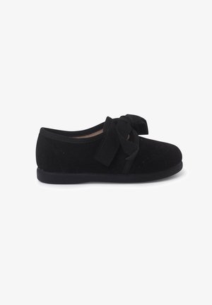 Zwarte suède ballerina's met een ronde neus, een gestructureerd oppervlak en een grote strikaccent aan de voorkant. Zachte binnenkant met een platte rubberen zool.