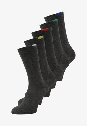 Calzini grigi scuri esposti in fila, con polsini a coste e accenti di colore contrastanti (rosso, giallo, verde, blu) nella parte superiore.