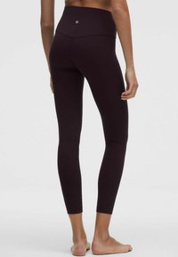 Visoko pasové črne leggings made of smooth, stretchy fabric. Imajo subtilen logotip na hrbtni strani in obliko, ki se prilega telesu.