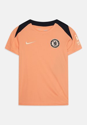Oranžinė sportinė apranga su juodais pečių akcentais, turinti apvalų kaklą, trumpas rankoves ir Chelsea FC logotipą ant krūtinės.