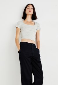 Gray cropped top with a square neckline, short sleeves. Paired with black wide-leg pants featuring pockets and a button closure.