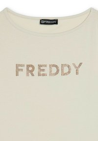 T-shirt in cotone beige con collo rotondo e "FREDDY" in borchie dorate metalliche come dettaglio decorativo. Tessuto liscio, vestibilità casual.