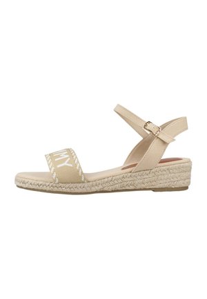 Sandales espadrilles beiges avec une sangle en toile affichant un texte blanc, un talon compensé en jute tressé et une sangle à la cheville avec une boucle.