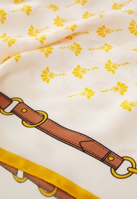 Silk tørklæde med et gentaget gult blomstermønster på en hvid baggrund, med et trykt brunt bælte design langs den nederste kant.