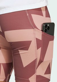 High-waisted leggings in pink and beige geometric pattern, featuring an outer pocket for a smartphone and flatlock stitching for comfort.
