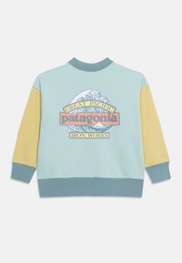 Ανοιχτό μπλε φούτερ με κίτρινες μανίκες και λογότυπο της Patagonia, κύμα και γραφικό βουνού σε παστέλ χρώματα στην πλάτη.