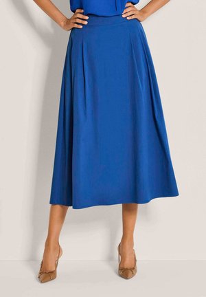 Blauer A-Linien-Rock mit glatter Textur, plissiertem Design, knielang, kombiniert mit nudefarbenen Slip-On-Absätzen für einen Kontrast.