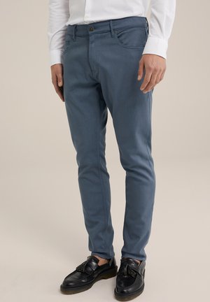 Pantalones ajustados de color azul, confeccionados en una tela ligera, que presentan un sutil estiramiento, bolsillos frontales y un cierre estándar de botón y cremallera.