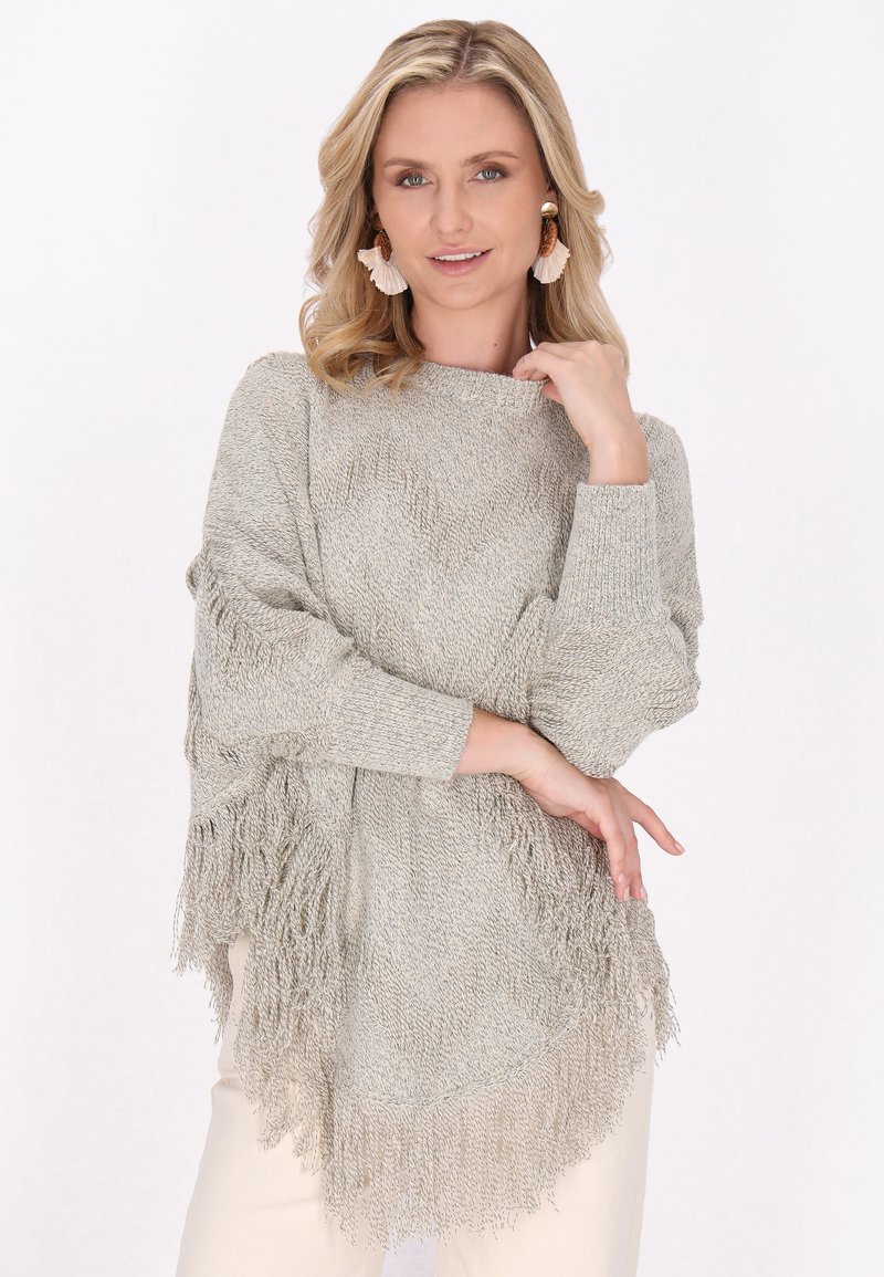 Maglione grigio chiaro con frange, lavorazione a maglia testurizzata, maniche larghe e orlo arrotondato, abbinato a pantaloni di colore neutro.