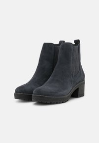 Bottines en daim gris foncé avec un bout arrondi, des panneaux latéraux élastiques et un talon bloc. Présentent des accents texturés et une semelle extérieure en caoutchouc.