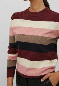 Gestreepte trui in kastanjebruin, roze, crème, bruin en marineblauw. Voorzien van een geribde halslijn en lange mouwen, met een gebreide textuur.