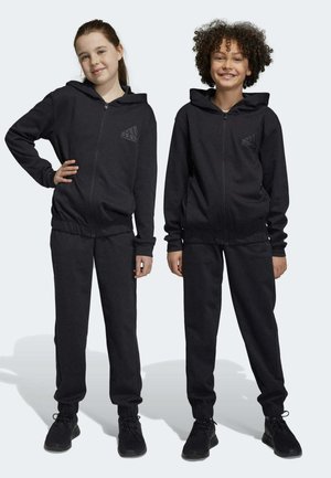 Felpe con zip nera e cappuccio, dotate di tasche frontali e polsini elastici, abbinate a pantaloni jogger coordinati. Presentano un logo discreto sul petto.