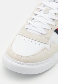 Sneakers bianche in pelle con dettagli in suede beige, punta rotonda, dettagli perforati e lacci bianchi. Suola in gomma piatta con bordi cuciti.
