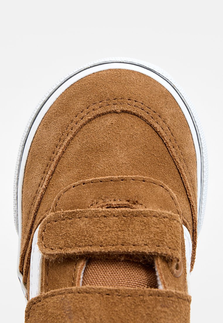 Brązowe zamszowe trampki z białą gumową podeszwą i rzepem. Okrągły czubek, teksturowana powierzchnia oraz widoczne detale przeszycia.