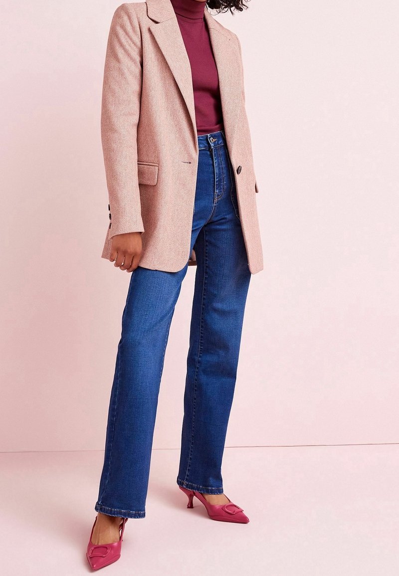 Světle růžový blejzr přes vínový rolák, doplněný modrými rovnými džíny a růžovými lodičkami na podpatku s mašlí.