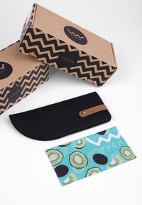 Černý plstěný pencil case s hnědým koženým akcentem, umístěný vedle dvou hnědých krabiček s černým zigzagovým vzorem a logem "VUCH", s barevným kartičkovým vzorem kiwi.