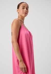 Ροζ αμάνικο φόρεμα με χαλαρή εφαρμογή, με λεπτό σχέδιο με κουκίδες και συγκεντρωμένη λεπτομέρεια στο μπροστινό μέρος. Λείος υφασμάτινος υφή.