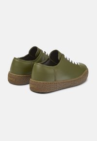 Sneakers in pelle verde oliva con lacci bianchi, forma arrotondata, suola in gomma e dettagli testurizzati marroni. Logo visibile sul tallone.