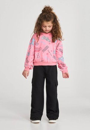 Felpa rosa con vari testi stampati e grafiche, abbinata a pantaloni cargo neri a gamba larga con tasche laterali.