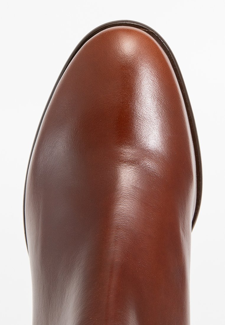 Stivale alla caviglia in pelle marrone con una finitura liscia, forma della punta ovale e cuciture minime. Presenta un aspetto elegante e lucido.