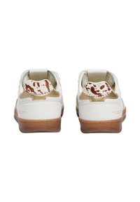 Baskets en cuir blanc avec des accents marron et des détails imprimés vache au talon, dotées d'un col rembourré et d'une semelle en caoutchouc texturée.