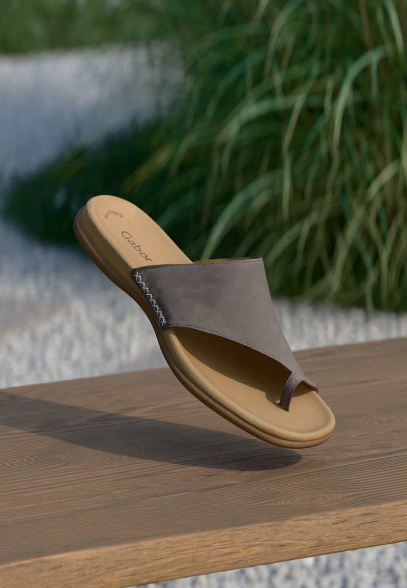 Sandalo scivoloso in pelle grigia con un anello per le dita e una suola in gomma beige, caratterizzato da cuciture decorative lungo il lato.