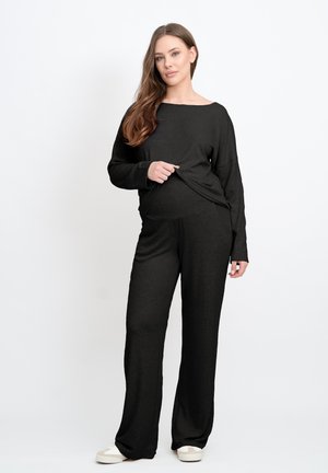 Schwarzes Loungewear-Set aus weichem Stoff, bestehend aus einem lockeren Oberteil mit weitem Ausschnitt und entspannten Hosen mit leichtem Schlag.