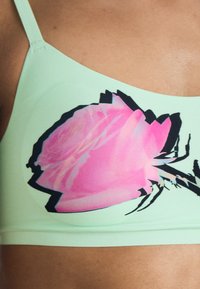 Mintgrön bralette med en stor rosa och svart ros-grafik. Mjuk tyg med en slät yta; utan bygel eller vaddering.