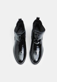 Botines de charol negro con paneles laterales elásticos, punta redondeada y una pequeña lengüeta; acabado suave y brillante.