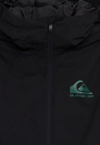 Črna jakna odporna na vreme z zadrgo spredaj, nastavljivo kapturico in zelenim logotipom Quiksilver na levem prsnem delu. Gladka tekstura.