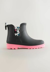 Botte de cheville en caoutchouc noir avec une semelle rose, surface texturée et doublure intérieure à imprimé léopard. Équipée d'une languette pour faciliter l'enfilage.