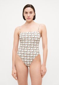 One-piece swimsuit with a square neckline, thin straps, and a multicolored floral pattern on a cream background. High-cut leg openings.