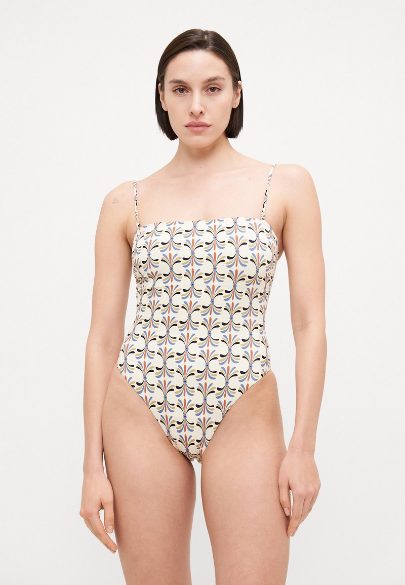 One-piece swimsuit with a square neckline, thin straps, and a multicolored floral pattern on a cream background. High-cut leg openings.