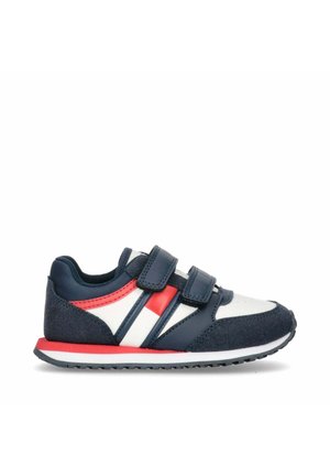 Chaussure de sport Velcro avec un dessus bleu marine et blanc, accents rouges, matériaux texturés et semelle en caoutchouc flexible.