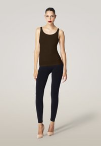 Brun linne parat med mörka leggings och nudefärgade högklackade skor. Slät textur med figurnära design och breda axelremmar.