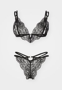 Ensemble de lingerie en dentelle noire comprenant un bralette avec des bretelles réglables et un thong assorti avec des motifs floraux délicats et des accessoires en forme de cœur.