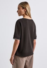 Ontspannen pasvorm donkerbruin sweatshirt met korte mouwen, witte accenten bij de manchetten en een brede halslijn. Zachte stof met een gladde textuur.