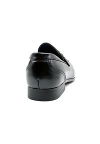 Chaussure en cuir noir avec un bout arrondi, finition lisse et petit talon. Elle présente des coutures minimales et un design subtil à l'arrière.