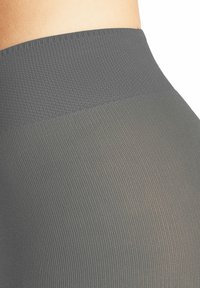 Szare legginsy w wysokim stanie z fakturowanym, prążkowanym wzorem. Materiał jest gładki, przechodzący od ciemniejszego do jaśniejszego odcienia.