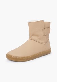 Beżowy skórzany botek za kostkę z zaokrąglonym noskiem, paskiem na rzep oraz miękką wyściółką wewnętrzną. Posiada gumową podeszwę i przeszycia jako ozdobę.