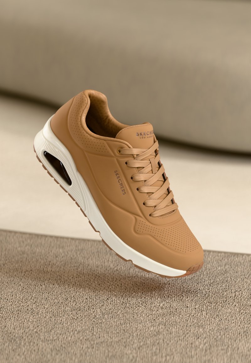 Bruna sneakers med slätt läderöverdel, perforerade detaljer, rund tå, vadderad sula och vit mellansula. Varumärkeslogotyp på sidan.