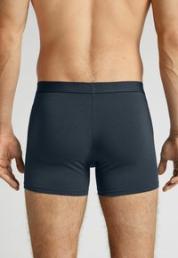 Mörkgrå herrboxershorts i stretchigt material; har midjeband utan sömmar och en kroppsnära passform.