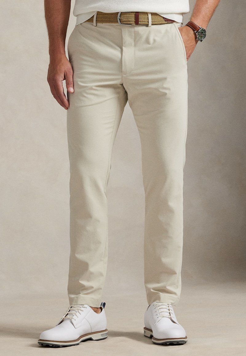 Μπεζ chinos με ευθεία γραμμή, από ελαφ ρύ ύφασμα. Συνδυάζονται με λευκά παπούτσια και πλεκτή ζώνη σε χρυσούς και καφέ τόνους.