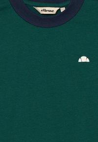 Mörkgrön t-shirt med marinblå krage och en liten vit halvcirkel-logotyp på vänster bröst, märkt för 10-11 år.